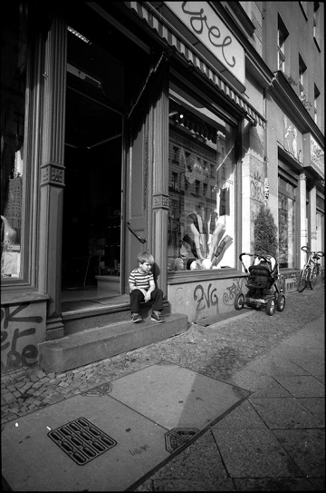 Das Einkaufen hat den Jungen auf der Ladentreppe offensichtlich ziemlich erschöpft. Oranienburger Straße, Kreuzberg